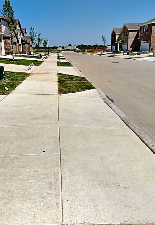 View of concrete road featuring sidewalks and a residential view | Image 38