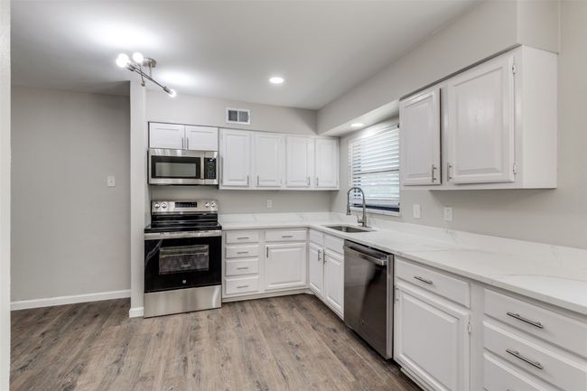Kitchen featuring appliances with stainless steel finishes, light wood-type flooring, white cabinetry, and recessed lighting | Image 12