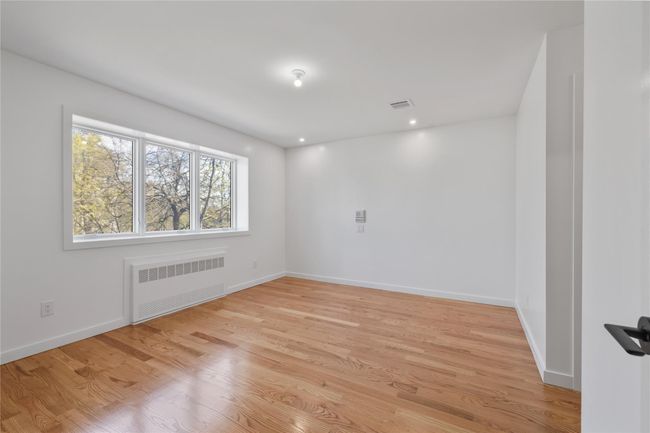 Spare room featuring radiator, light wood-style floors, visible vents, and baseboards | Image 23