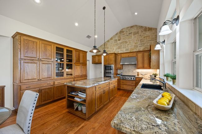 The kitchen features granite countertops, custom cabinetry, and abundant storage—including convenient pull-out drawers in most lower cabinets. Thoughtfully designed for both beauty and function. | Image 12