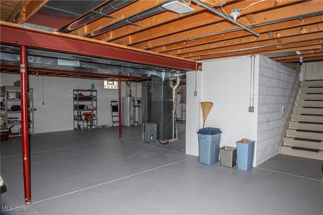Unfinished below grade area with heating unit, stairs, and gas water heater | Image 21