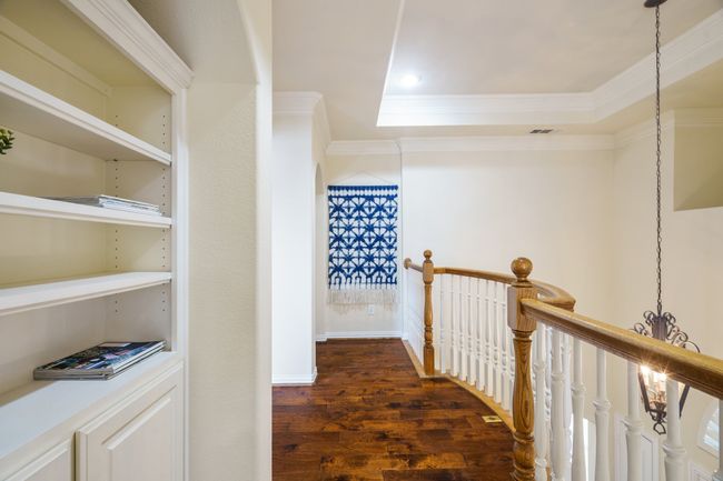 Hallway with a tray ceiling, an upstairs landing, wood floors, and ornamental molding | Image 13