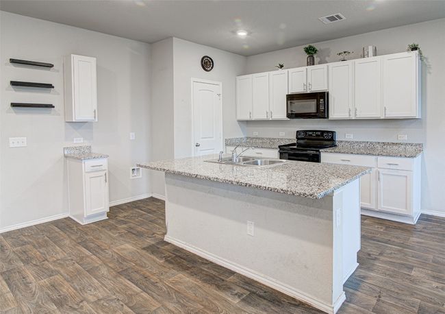 Kitchen with white cabinetry, visible vents, black appliances, a sink, and dark wood-style floors | Image 13