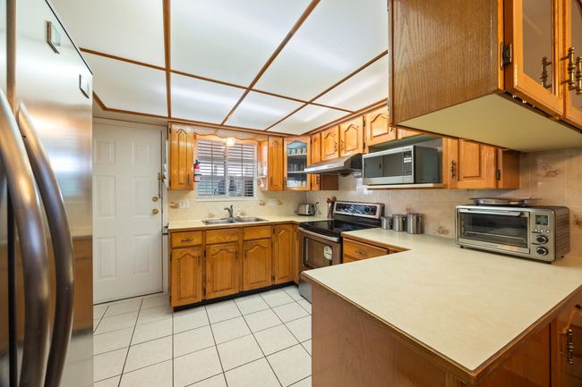 Kitchen with appliances with stainless steel finishes, a sink, brown cabinetry, and under cabinet range hood | Image 20