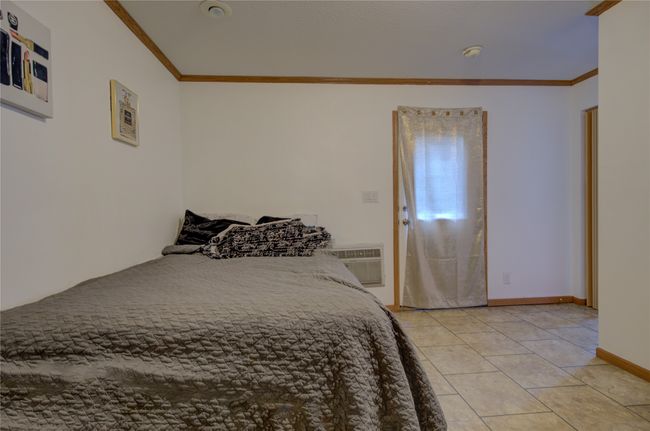 Bedroom featuring baseboards, a wall mounted air conditioner, ornamental molding, and light tile patterned floors | Image 7