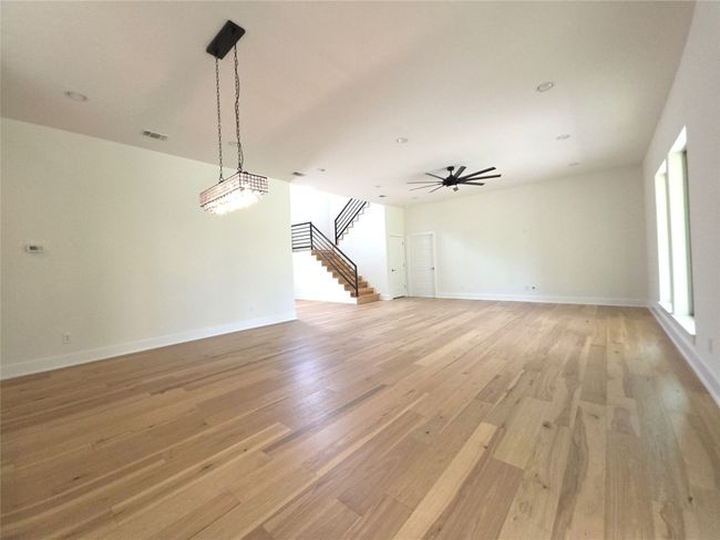 Unfurnished living room with stairway, light wood-type flooring, baseboards, and ceiling fan | Image 9