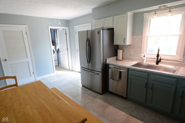 kitchen featuring washing machine and clothes dryer, a sink, light tile patterned floors, stainless steel appliances, and light countertops | Image 25