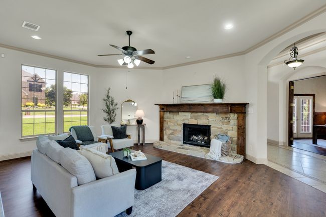 Living area with a ceiling fan, arched walkways, ornamental molding, a fireplace, and wood finished floors | Image 6