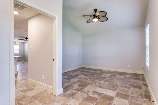 Spare room featuring a ceiling fan, lofted ceiling, and light stone finish flooring | Image 13