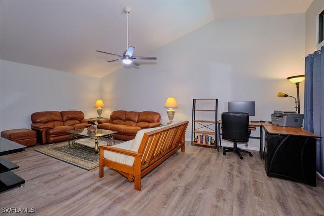 Living area featuring lofted ceiling, light wood finished floors, ceiling fan, and a desk | Image 7