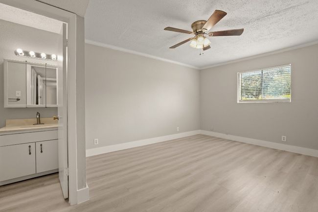 Empty room featuring a textured ceiling, crown molding, ceiling fan, and light wood-style flooring | Image 23