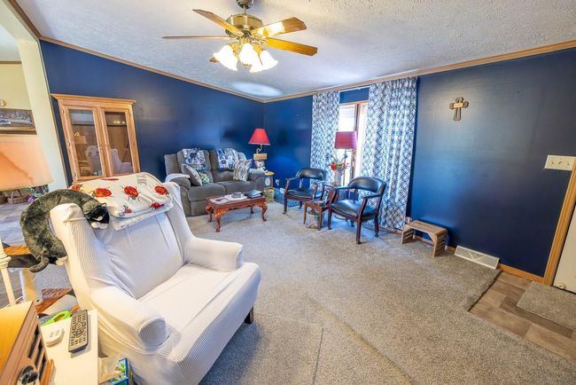 Living room featuring a textured ceiling, crown molding, visible vents, vaulted ceiling, and a ceiling fan | Image 20