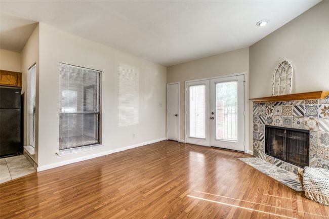Living room with french doors, light wood-style flooring, a fireplace with flush hearth, and baseboards | Image 7