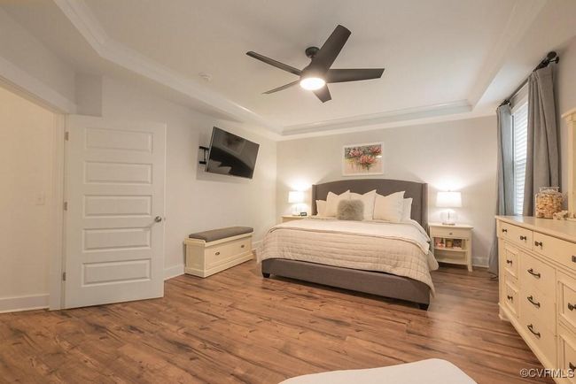 Bedroom with a tray ceiling, wood finished floors, ceiling fan, and crown molding | Image 15