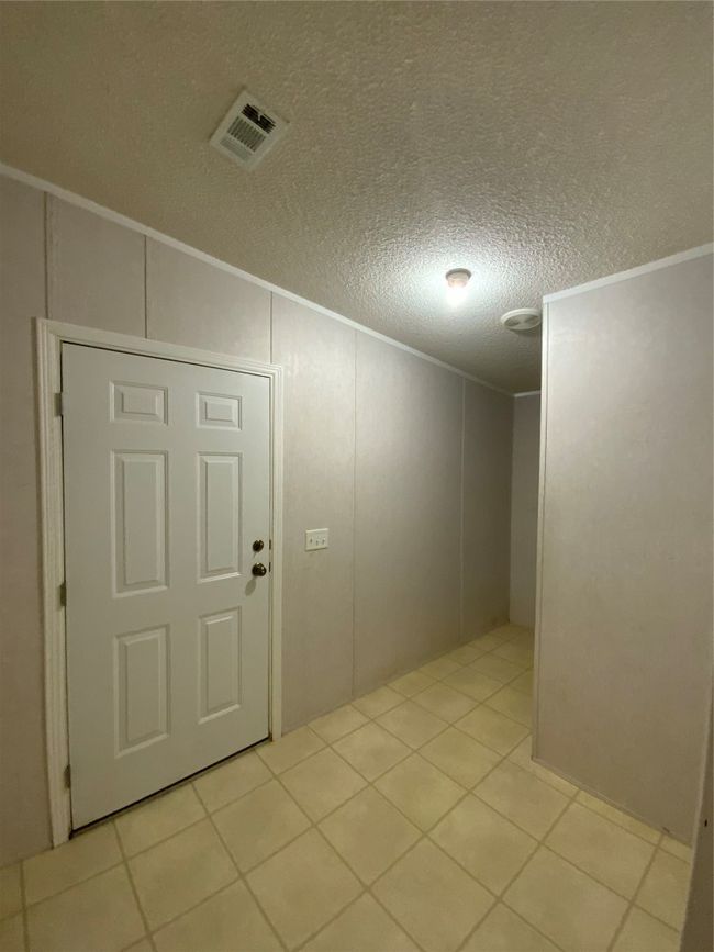 Tiled empty room with a decorative wall, visible vents, crown molding, and a textured ceiling | Image 30