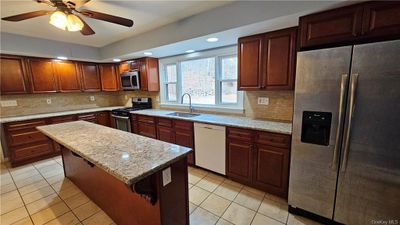 Kitchen featuring appliances with stainless steel finishes, sink, a kitchen island, and backsplash | Image 2