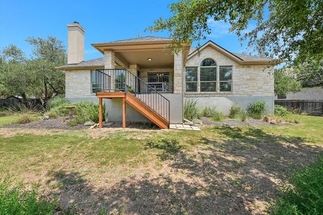 Back of property with stone siding, stairs, a chimney, and roof with shingles | Image 23