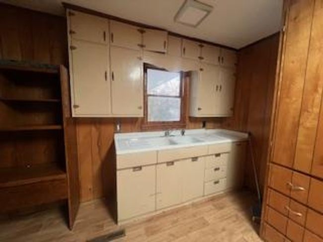 Kitchen featuring light wood-type flooring, a sink, wooden walls, and open shelves | Image 11