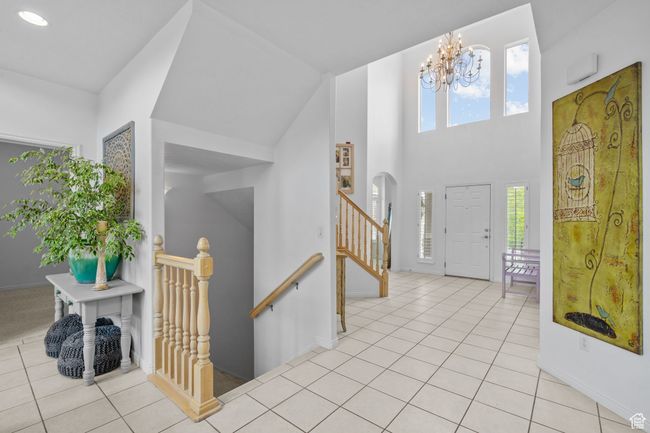 Entrance foyer featuring light tile patterned flooring, a notable chandelier, recessed lighting, baseboards, and a towering ceiling | Image 9