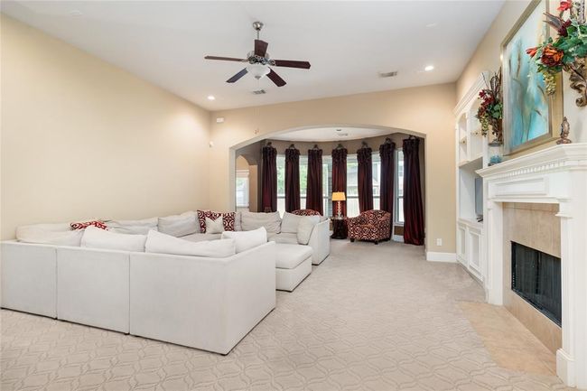 The formal living room offers an impressive sense of space, anchored by a stunning bay window that floods the room with natural light and offers a serene view of the expansive backyard. A gas fireplace adds warmth and charm, making this a standout feature of the home. | Image 12