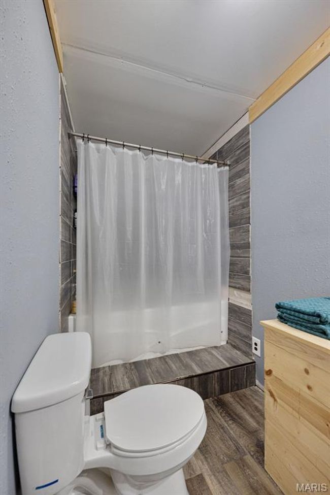 Bathroom with toilet, wood finished floors, and shower / bath combo | Image 11