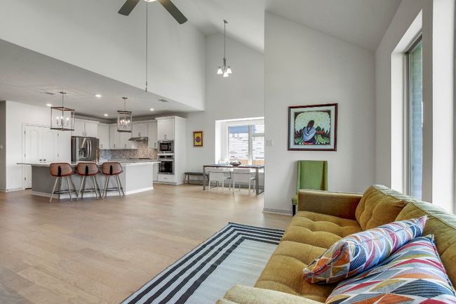 Living room with light wood finished floors, lofted ceiling, a ceiling fan, a chandelier, and recessed lighting | Image 13
