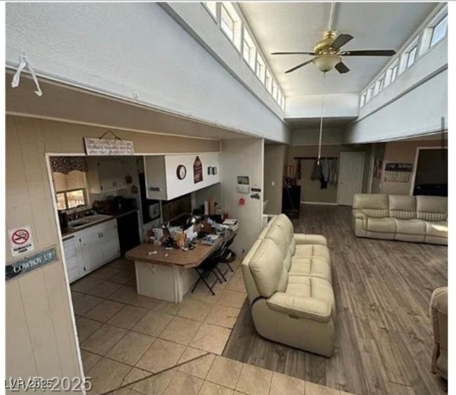 Living area featuring a towering ceiling, a ceiling fan, and wood finished floors | Image 8