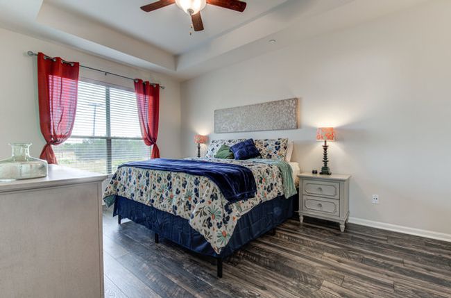 Bedroom featuring wood finished floors, baseboards, a raised ceiling, and a ceiling fan | Image 6
