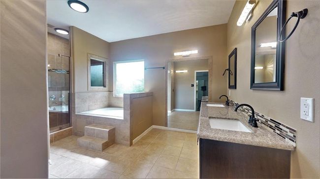 Experience luxury in the newly updated primary bathroom, featuring double sinks, a jacuzzi tub with steps, a dual shower head, and an expansive wall mirror. | Image 23