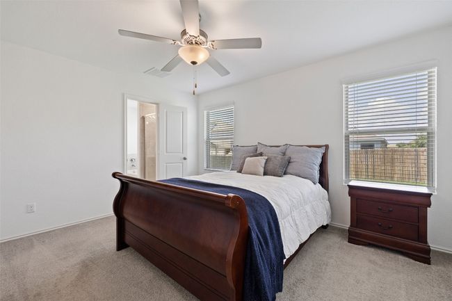 Bedroom featuring light colored carpet, ceiling fan, and ensuite bathroom | Image 16