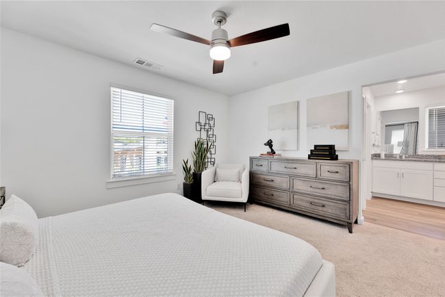 Bedroom featuring a ceiling fan, light colored carpet, visible vents, and connected bathroom | Image 17