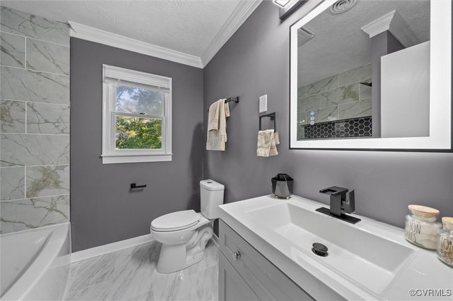 Bathroom featuring marble look tiles, a textured ceiling, vanity, and crown molding | Image 22
