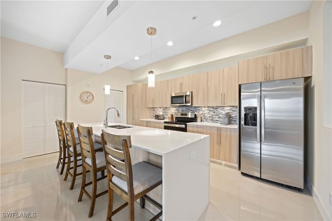 Kitchen with decorative backsplash, light brown cabinets, a sink, and appliances with stainless steel finishes | Image 17