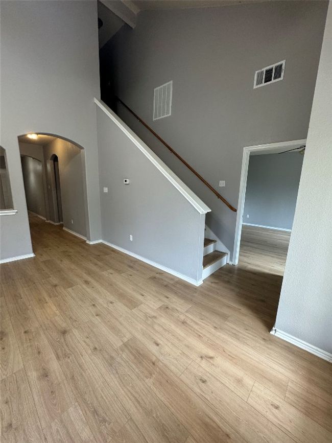 Unfurnished living room featuring arched walkways, high vaulted ceiling, wood finished floors, stairway, and beam ceiling | Image 14