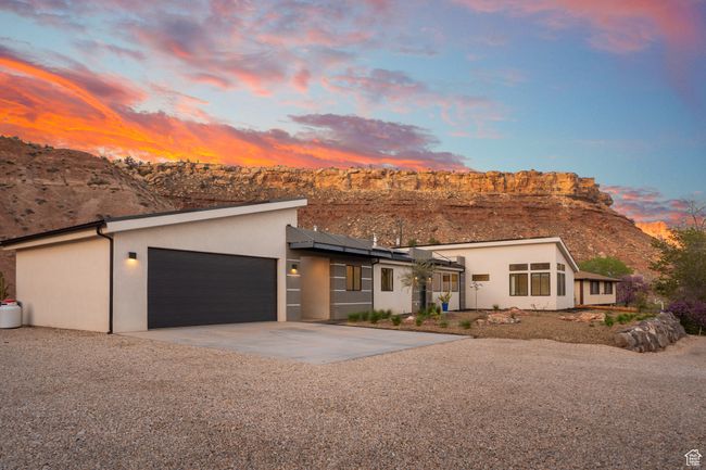 View of front of property featuring concrete driveway, stucco siding, a garage, and solar panels | Image 59