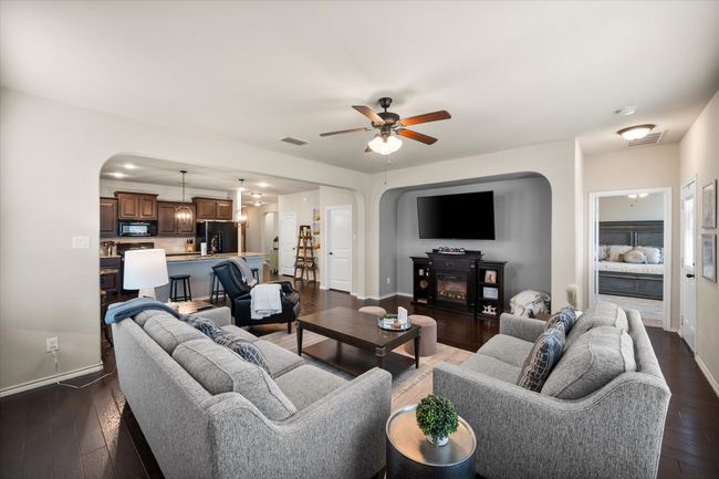Living room with dark wood-style flooring, visible vents, a ceiling fan, and arched walkways | Image 22