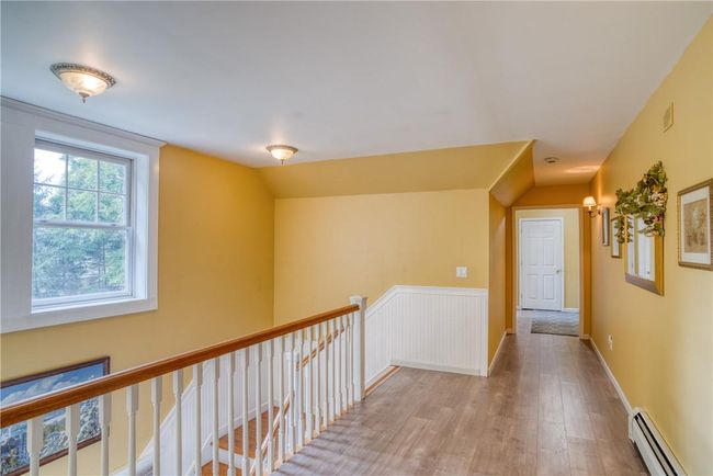 Hallway featuring hardwood / wood-style flooring, a baseboard heating unit, and vaulted ceiling | Image 22