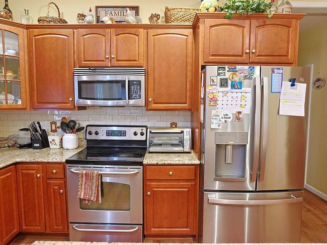 Kitchen with a toaster, backsplash, light stone countertops, appliances with stainless steel finishes, and glass insert cabinets | Image 10