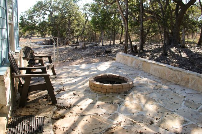 At the back of the tiny home is a stone patio with a fire pit | Image 26