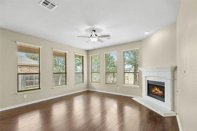 Unfurnished living room featuring a ceiling fan, baseboards, dark wood-style flooring, and a glass covered fireplace | Image 10
