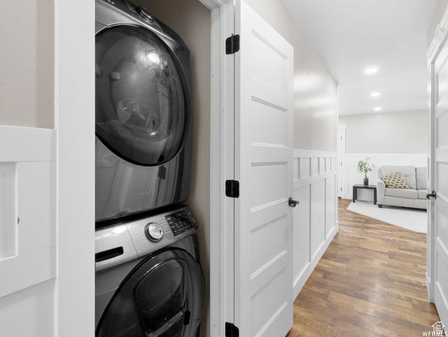 Laundry room with stacked washing machine and dryer, light wood-style flooring, wainscoting, and recessed lighting | Image 6