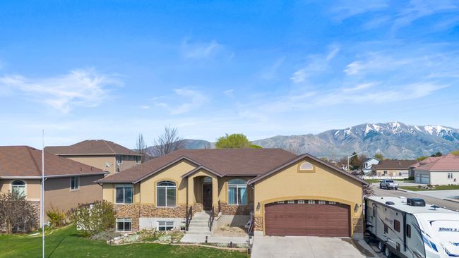 View of front of home featuring driveway, stone siding, a mountain view, an attached garage, and stucco siding | Image 43