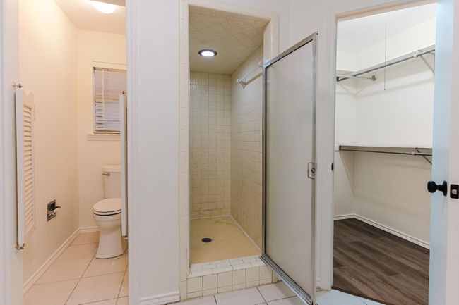 Full bath with tile patterned flooring, a walk in closet, toilet, baseboards, and a shower stall | Image 22