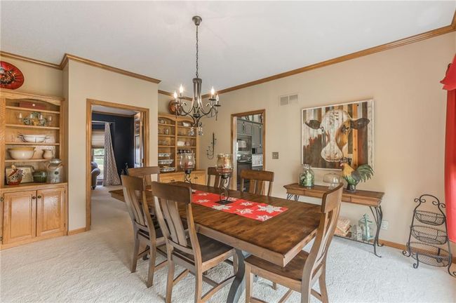 Dining space featuring a chandelier, crown molding, light carpet, and visible vents | Image 22
