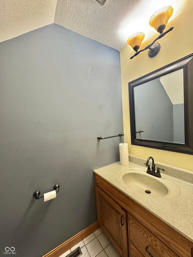 bathroom featuring a textured ceiling, vanity, tile patterned floors, baseboards, and vaulted ceiling | Image 52