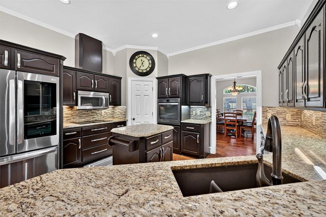 Kitchen with fridge, stainless steel microwave, a sink, crown molding, and backsplash | Image 16