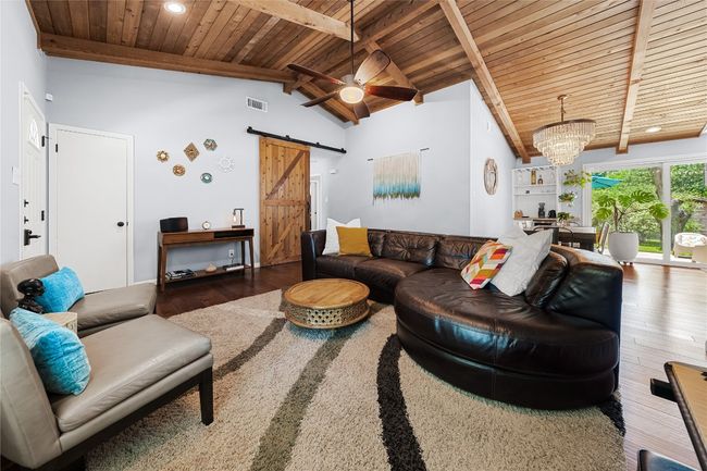 Living room with wood ceiling, a barn door, wood finished floors, a ceiling fan, and a chandelier | Image 8
