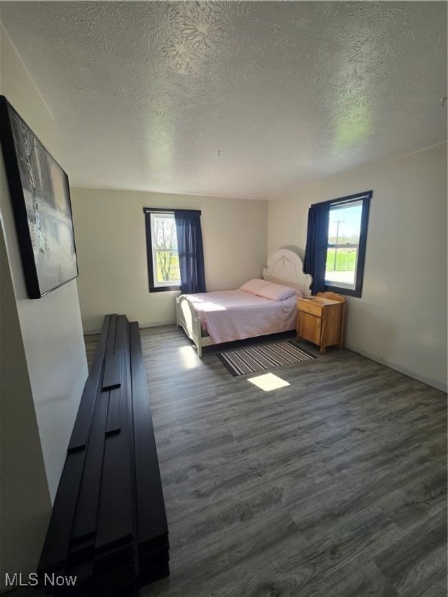 Bedroom featuring a textured ceiling, dark wood-style floors, and multiple windows | Image 15