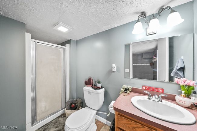 Bathroom with vanity, a shower with shower door, toilet, and a textured ceiling | Image 22