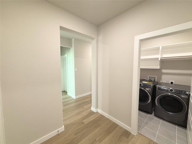 Washroom with washing machine and dryer and light wood-style floors | Image 26